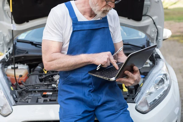 Mecânico usando laptop para verificar o motor do carro — Fotografia de Stock