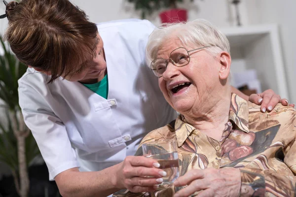 Infirmière donnant un verre d'eau à une femme âgée — Photo