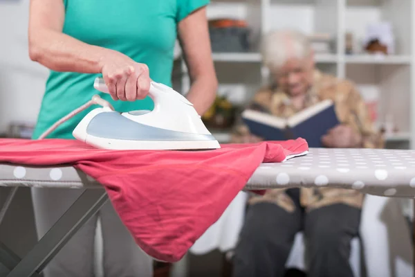 Home helper ironing clothes for an old woman