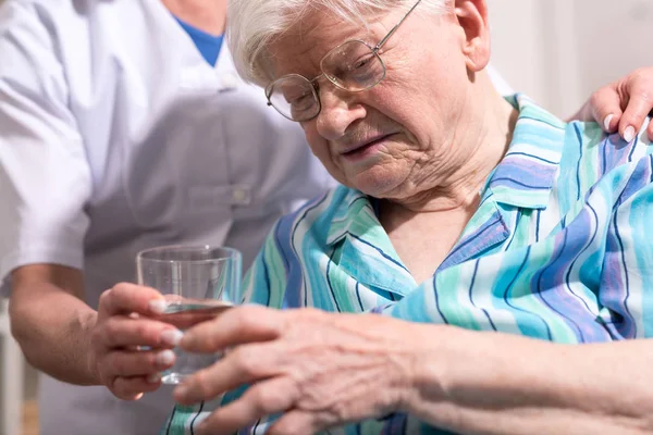 Enfermera dando vaso de agua a la mujer mayor — Foto de Stock