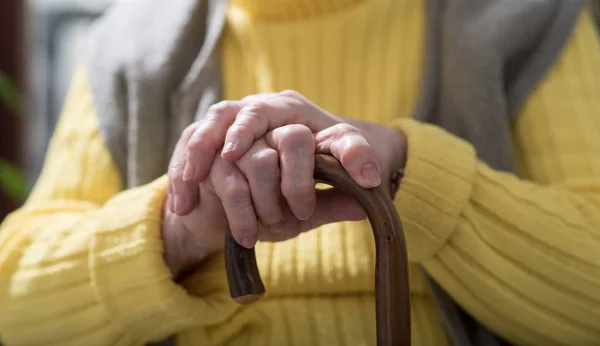 Old woman with her hands on a cane — Stock Photo, Image