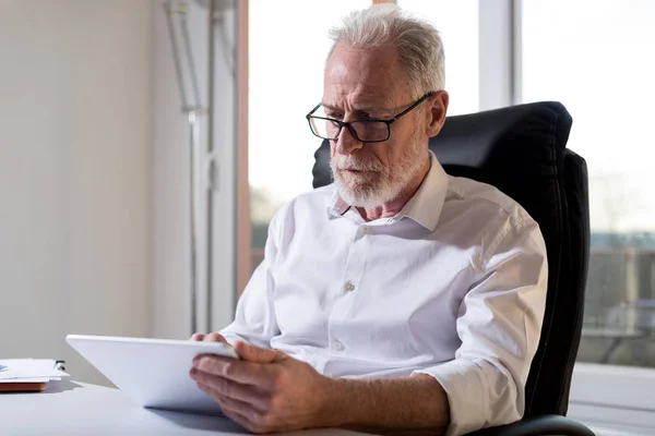 Senior affärsman med en digital tablett, hårt ljus — Stockfoto