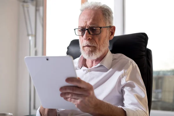 Senior affärsman med en digital tablett, hårt ljus — Stockfoto