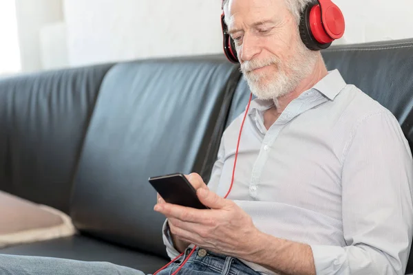 Сучасний зрілий чоловік слухає музику на мобільному телефоні — стокове фото