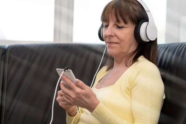 Mulher madura moderna ouvindo música no telefone móvel — Fotografia de Stock