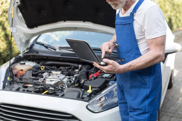 Monteur laptop gebruikt voor het controleren van de motor van auto — Stockfoto