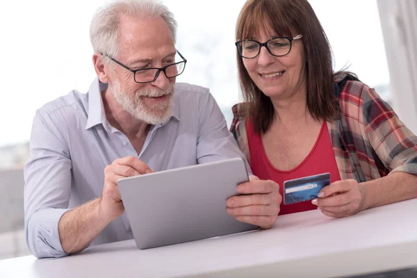 Mature couple shopping en ligne avec tablette et carte de crédit — Photo