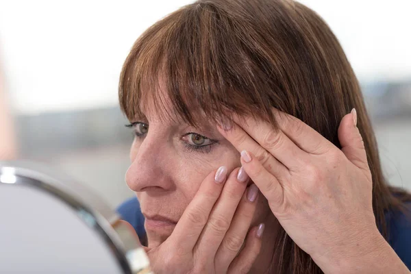 Mulher madura olhando para as rugas dos olhos — Fotografia de Stock