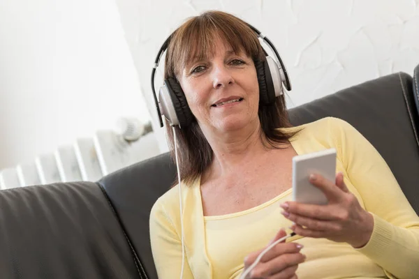 Mulher madura moderna ouvindo música no telefone móvel — Fotografia de Stock