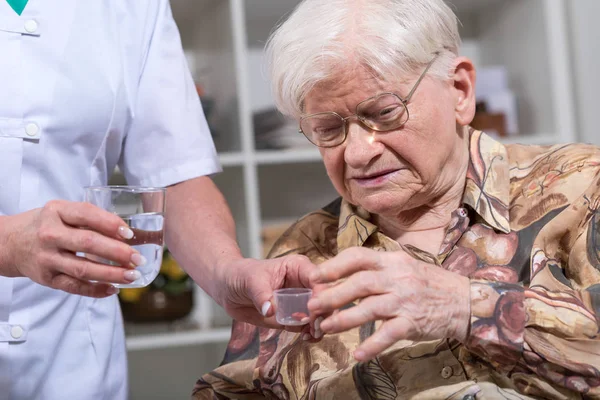 Zdravotní sestra dávat léky se starší ženou — Stock fotografie