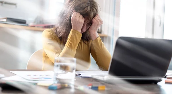 Стрессовая деловая женщина сидит в офисе, эффект световых лучей — стоковое фото