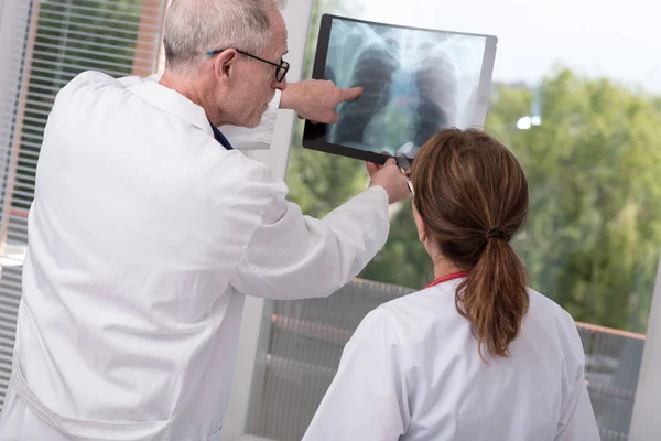 Dva lékaři zkoumat rentgenové zpráva — Stock fotografie