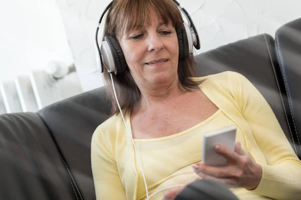 Moderna mogen kvinna lyssnar musik på mobiltelefon — Stockfoto