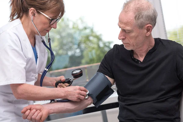 Médico midiendo la presión arterial con esfigmomanómetro — Foto de Stock