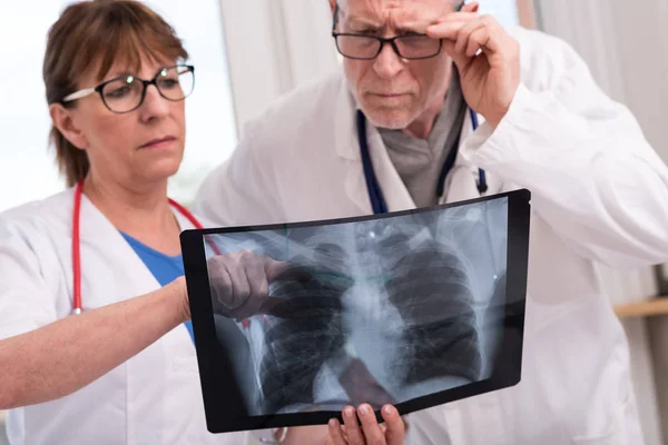 Zwei Ärzte untersuchen Röntgenbericht — Stockfoto