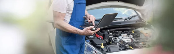 Mecânico usando laptop para verificar o motor do carro — Fotografia de Stock