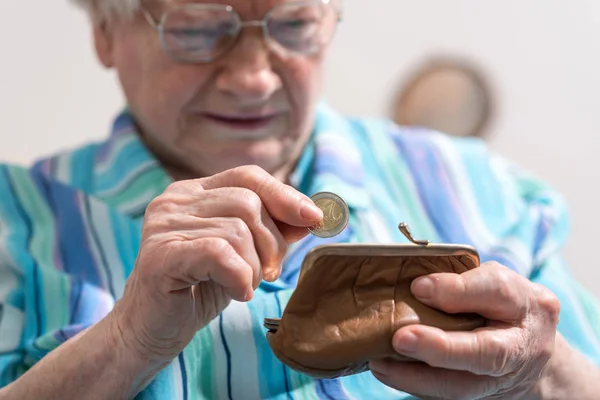 Старшая женщина вытаскивает монету из бумажника — стоковое фото