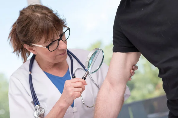 Dermatologista examinando a pele de um paciente — Fotografia de Stock