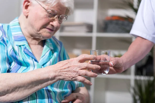 Verpleegkundige glas water geven aan senior vrouw — Stockfoto