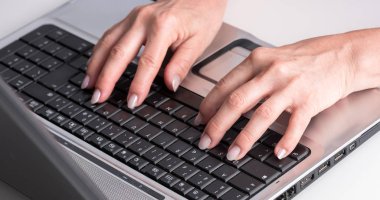 Eller dizüstü bilgisayarda klavyede yazıyor.