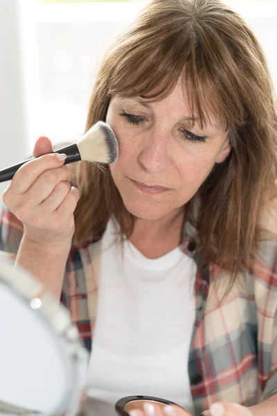 Mulher aplicando pó cosmético em seu rosto — Fotografia de Stock