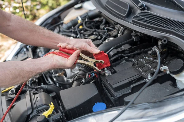 Handen van auto monteur met auto batterij jumper kabel — Stockfoto