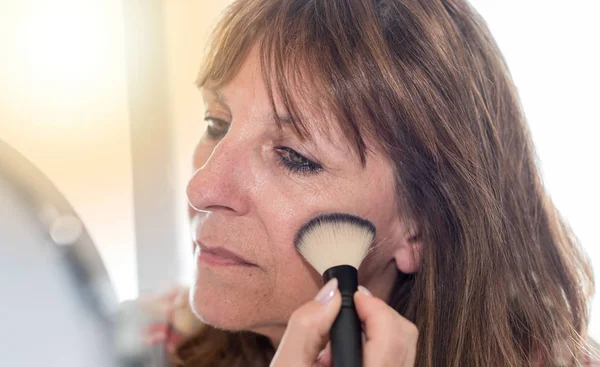 Mulher aplicando pó cosmético no rosto, efeito de luz — Fotografia de Stock