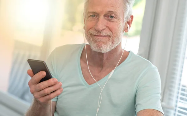 Porträtt av mogen man lyssnar musik med hörlurar, ljus eff — Stockfoto