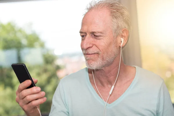 Retrato de hombre maduro escuchando música con auriculares, eff luz —  Fotos de Stock