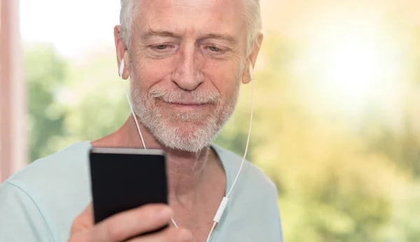 Porträtt av mogen man lyssnar musik med hörlurar, ljus eff — Stockfoto