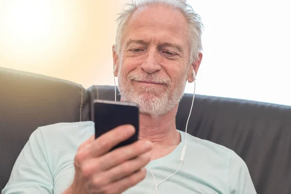 Porträtt av mogen man lyssnar musik med hörlurar, ljus eff — Stockfoto