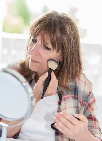 Mulher aplicando pó cosmético em seu rosto — Fotografia de Stock