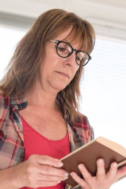 Kitap okuyan olgun bir kadın.