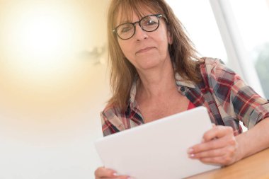 Olgun kadın kullanarak bir tablet, ışık efekti