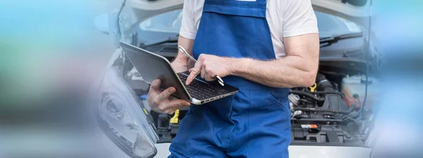 Mecânico usando laptop para verificar o motor do carro — Fotografia de Stock