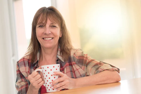 Retrato de mulher madura sorrindo e segurando uma caneca, efeito de luz — Fotografia de Stock