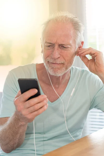 Porträtt av mogen man lyssnar musik med hörlurar, ljus eff — Stockfoto