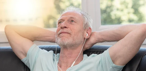 Portrait d'homme mûr écoutant de la musique avec écouteurs, lumière eff — Photo