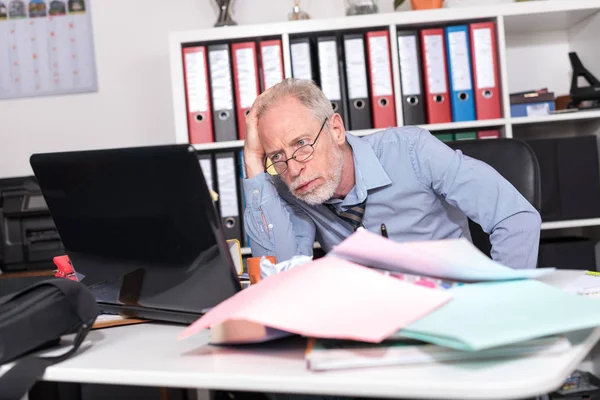 Überlasteter Geschäftsmann sitzt an unordentlichem Schreibtisch — Stockfoto