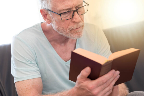 Portrait of mature man reading a book, light effect