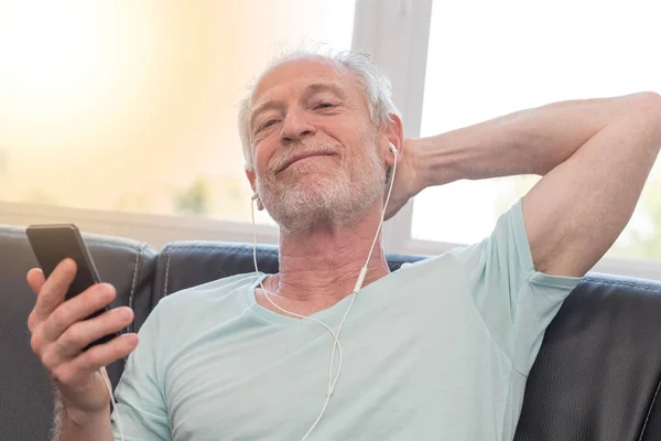 Olgun adam dinleme müzik kulaklık, ışık eff ile portresi — Stok fotoğraf