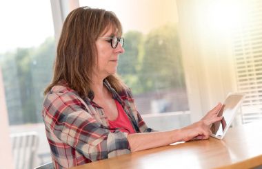 Olgun kadın kullanarak bir tablet, ışık efekti