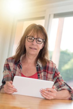 Olgun kadın kullanarak bir tablet, ışık efekti