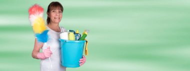 Bir toz bezi ve temizlik ekipmanları ile bir kova tutarak ev kadını