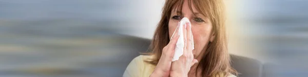 Mature woman blowing her nose — Stock Photo, Image