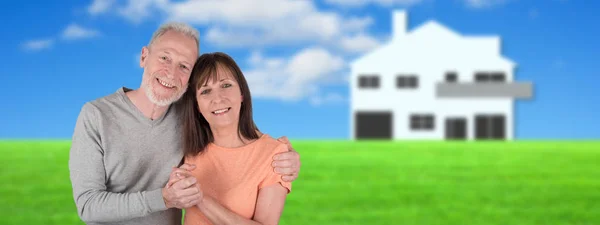 Starší pár objímat se svým domem v zázemí — Stock fotografie