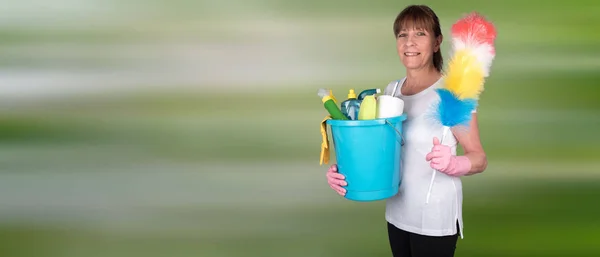 Housewife holding a duster and a bucket with cleaning equipment — Stock Photo, Image