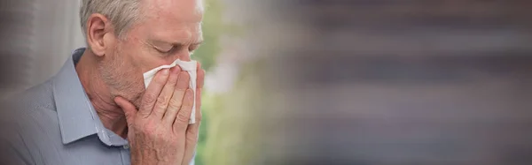 Hombre mayor sonándose la nariz — Foto de Stock