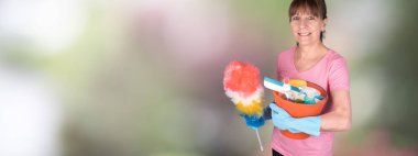 Bir toz bezi ve temizlik ekipmanları ile bir kova tutarak ev kadını