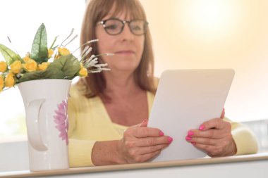 Evde, bir tablet kullanan kadın ıșık etkisi